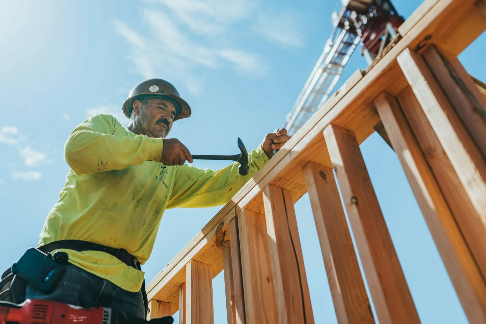 Charpentier au travail sur une charpente en bois, ciel dégagé